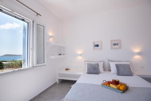 a white bedroom with a bed with a tray of fruit on it at Flora & Agelos Studios in Chrissi Akti
