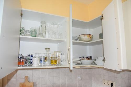 a kitchen with white cabinets filled with glassware at Ferienwohnung Heinrichseck in Bamberg