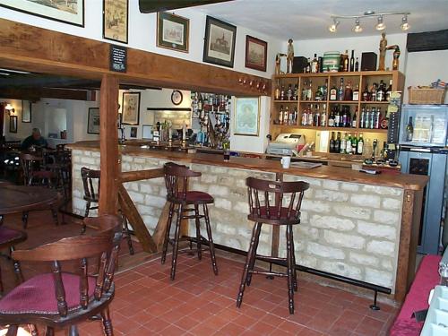 a bar in a restaurant with wooden stools at The Fox & Hounds in Faringdon