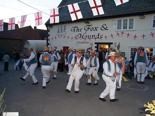 un grupo de hombres bailando frente a un edificio en The Fox & Hounds, en Faringdon