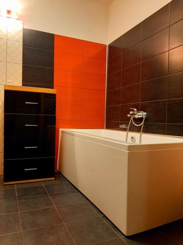 a bath tub in a bathroom with orange and black tiles at Champêtre Park View Apartments in Rīga