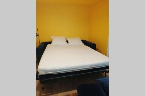 1 cama con sábanas blancas y almohadas en una habitación en CHARMANT APPARTEMENT AVEC TERRASSE, en Pont-de-lʼIsère
