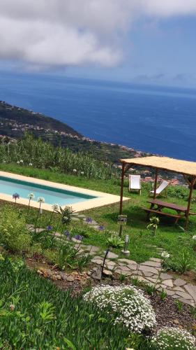 a picnic table next to a pool with the ocean at Calheta Glamping Pods - Nature Retreat in Calheta