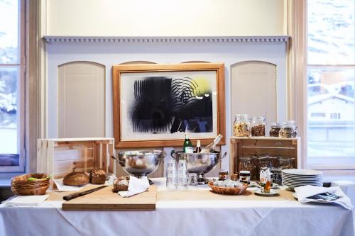 a table with a white table cloth and bowls on it at Maloja Palace Suites CO2-Neutral in Maloja