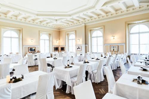 a banquet hall with white tables and white chairs at Maloja Palace Suites CO2-Neutral in Maloja