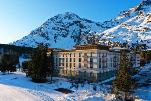 a building in front of a snow covered mountain at Maloja Palace Suites CO2-Neutral in Maloja