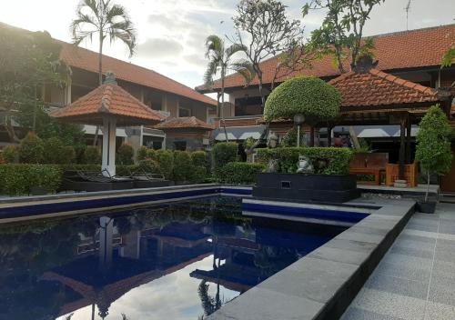 a swimming pool in front of a building at Dewa Bharata Bungalows Legian in Legian