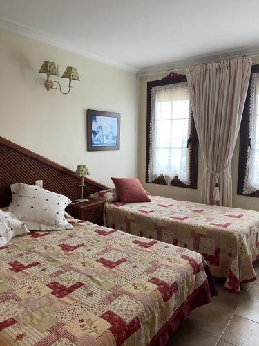 a bedroom with two beds and two windows at Posada de Seña in Seña