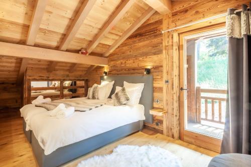 a log cabin bedroom with a bed and a window at Le Nordic in Morzine