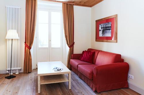 a living room with a red couch and a table at Maloja Palace Suites CO2-Neutral in Maloja