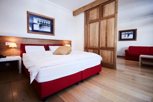 a bedroom with a large bed and a red couch at Maloja Palace Suites CO2-Neutral in Maloja