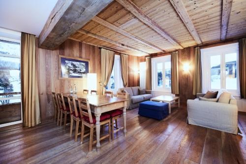 a dining room with a table and chairs and a couch at Maloja Palace Suites CO2-Neutral in Maloja