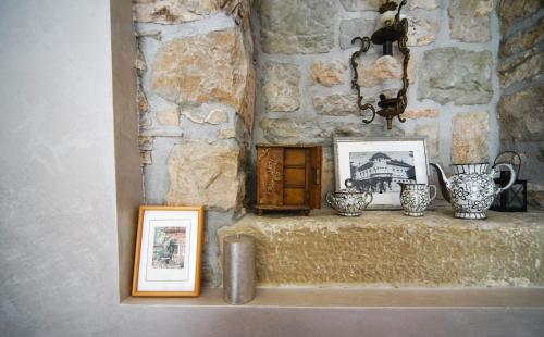 eine Steinmauer mit einem Regal mit Vasen und Bildern in der Unterkunft Stancija Ruseti in Oprtalj
