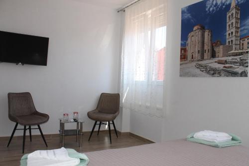 una camera con due sedie, un letto e una TV di Jeta Studio & Rooms a Zara (Zadar)