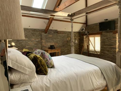 een slaapkamer met een groot wit bed en een bakstenen muur bij The Padstow Cottage (Coswarth House) in Padstow