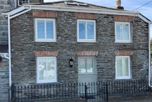 a brick house with blue shutters and a fence at The Padstow Cottage - Coswarth House in Padstow