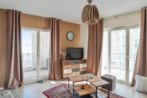 a living room with a tv and large windows at Cozy 1-bedroom with terrace - Bègles Welkeys in Bègles