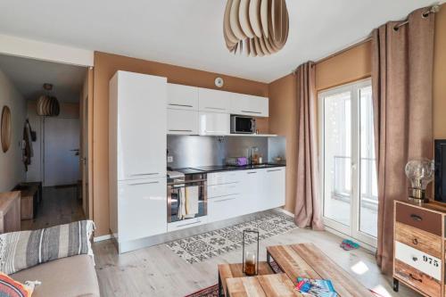 a living room with a kitchen with white cabinets at Cozy 1-bedroom with terrace - Bègles Welkeys in Bègles
