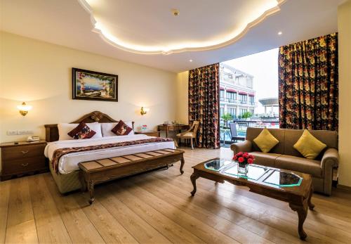 ein Schlafzimmer mit einem Bett, einem Sofa und einem Tisch in der Unterkunft Welcomhotel by ITC Hotels, Bella Vista, Panchkula - Chandigarh in Chandīgarh