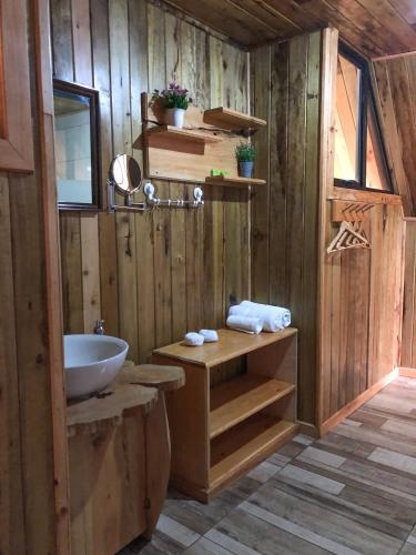 a bathroom with a wooden wall with a sink at Tityra Lodge in Monteverde Costa Rica