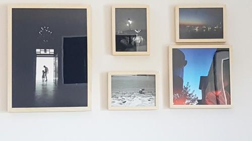 a group of framed photographs on a wall at Eva Beach Studio in Néa Péramos