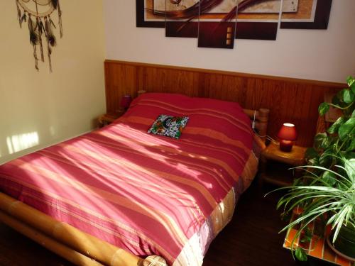 ein Schlafzimmer mit einem Bett mit roter Bettwäsche und einer Pflanze in der Unterkunft La Maison des Lys in Chissey-lès-Mâcon