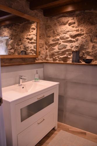 ein Badezimmer mit einem Waschbecken und einer Steinmauer in der Unterkunft O XARDÍN DA FRAGA in San Salvador