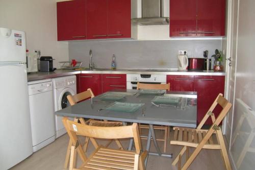 une cuisine avec des armoires rouges et une table et des chaises dans l'établissement Charmante maisonnette aux portes de paris, à Saint-Ouen