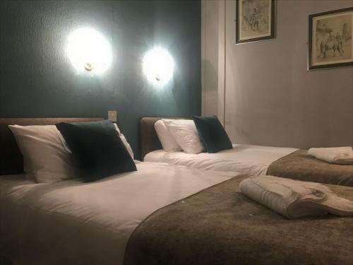 two beds in a room with white sheets and pillows at Newcastle House Rothbury in Rothbury