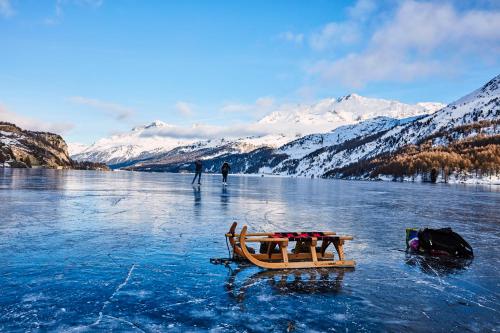 a boat in the middle of a lake with snow covered mountains at Maloja Palace Residence Engadin-St Moritz CO2-Neutral in Maloja
