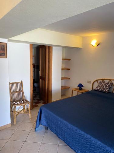 a bedroom with a blue bed and a chair at Casa Salina in Santa Marina Salina