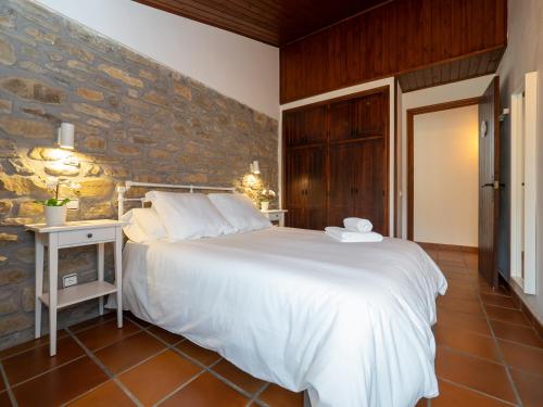 1 dormitorio con 1 cama blanca grande y pared de piedra en eva y maría CASA RURAL, en Rañín