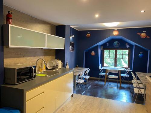 a kitchen with blue walls and a table with a microwave at Hostel Galaxy in Gdańsk