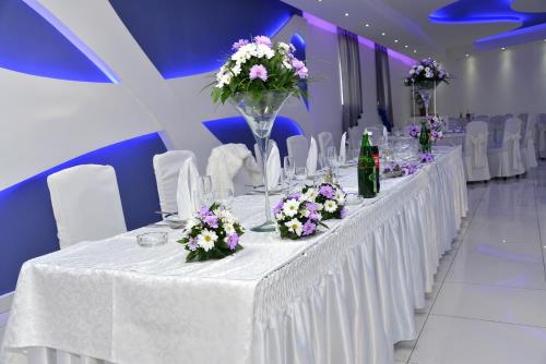 a long white table with white chairs and flowers on it at Vazdušna Banja in Niš