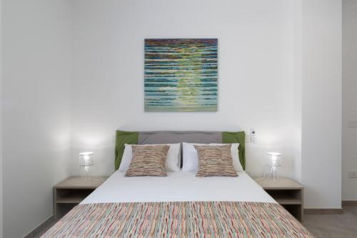 a bedroom with a white bed with two lamps at B&B Domus Terra Mare in Torre San Giovanni Ugento