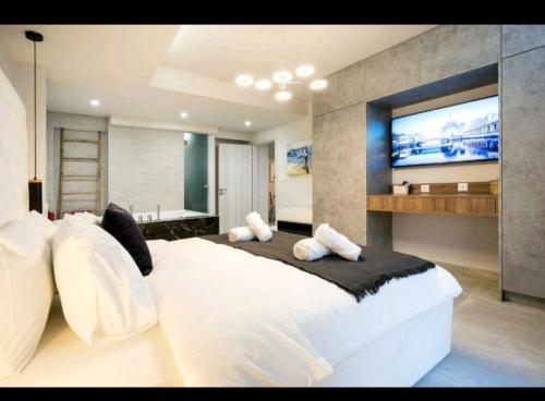 a bedroom with a large white bed with a flat screen tv at Romantic Jacuzzi Apartment in Athens