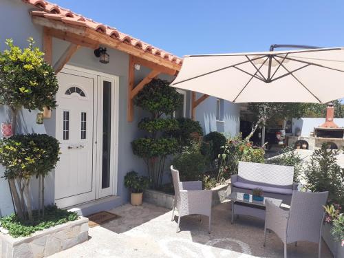 a patio with a white door and chairs and an umbrella at Vasiliki Residence in Pylos