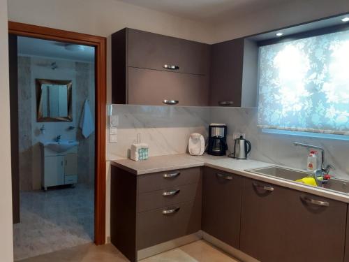 d'une cuisine avec des placards bruns, un évier et une fenêtre. dans l'établissement Vasiliki Residence, à Pylos