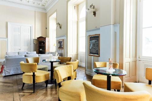 a living room with yellow chairs and tables at Maloja Palace Residence Engadin-St Moritz CO2-Neutral in Maloja