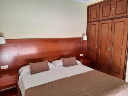 Schlafzimmer mit einem großen Bett mit einem Kopfteil aus Holz in der Unterkunft Hotel Cervantes in Sanxenxo