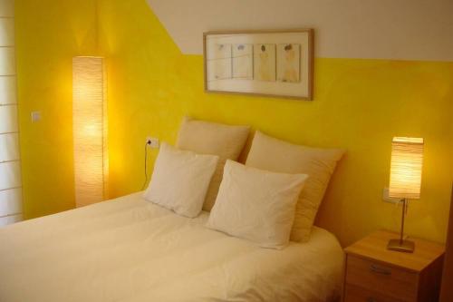 ein Schlafzimmer mit einem weißen Bett mit gelben Wänden in der Unterkunft Tresmall in Les Cases d'Alcanar