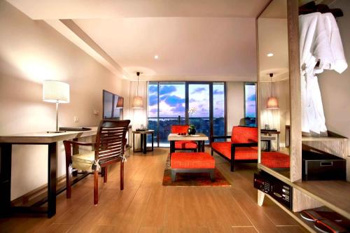 a living room with a desk and chairs and a room at Harper Kuta Hotel by ASTON in Legian