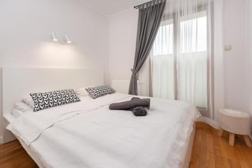 uma cama branca num quarto com uma janela em Morskie Apartamenty "Neptun" em Jastrzebia Gora