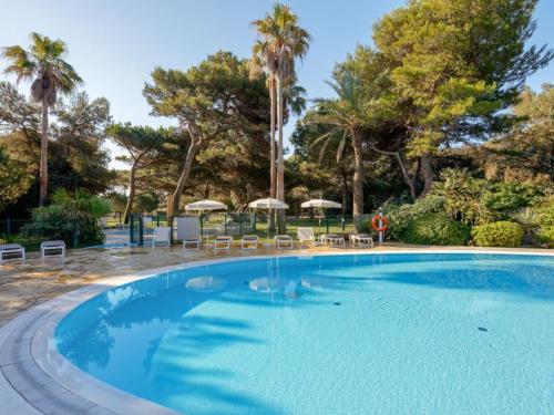 uma grande piscina azul com cadeiras e guarda-sóis em BADINE BEACH 5p Plage piscine balnéo clim jardin éxotique em Hyères