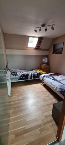 twee bedden in een kamer met houten vloeren en een raam bij L orée du Saint-Gangolphe in Lautenbach