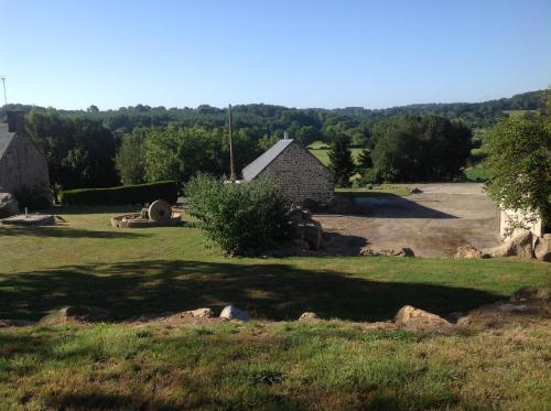 a yard with a stone house and a driveway at LES ROCAILLES in La Forêt-Auvray