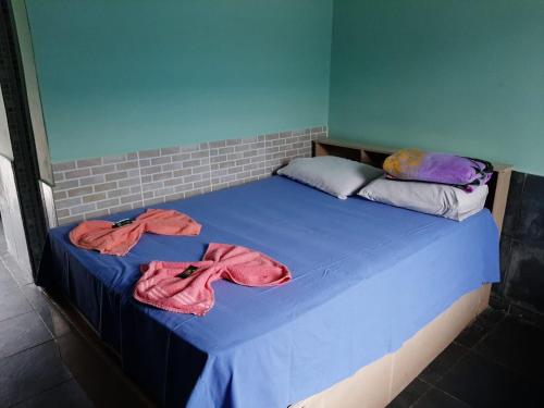 uma cama com lençóis azuis e toalhas cor-de-rosa em Pousada Alojamento Fragoso em Itaguaí
