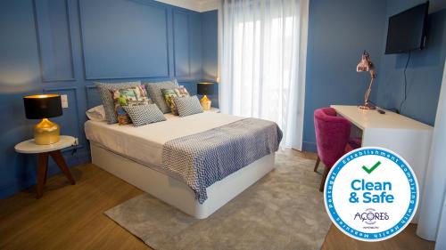 Schlafzimmer mit einem Bett mit blauen Wänden und einem TV in der Unterkunft ZIGZAG HOSTEL in Praia da Vitória