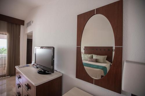 1 dormitorio con cama y espejo en la pared en The Royal Cancun All Villas Resort, en Cancún