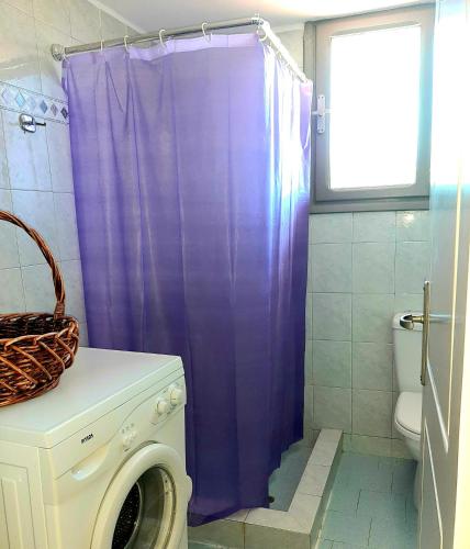 a purple shower curtain in a bathroom with a washing machine at Villa Konari in Tolo